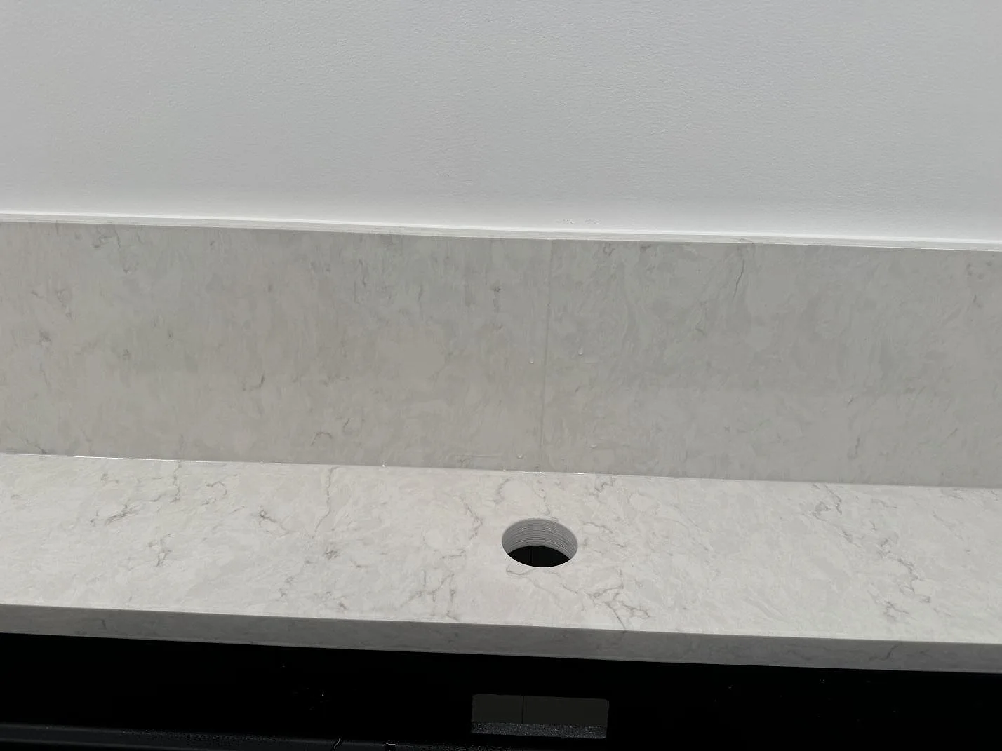 Detalj av blandarhål, stänkkant och ljus ådring i polerad Silestone Snowy Ibiza bänkskiva i Staffanstorp.