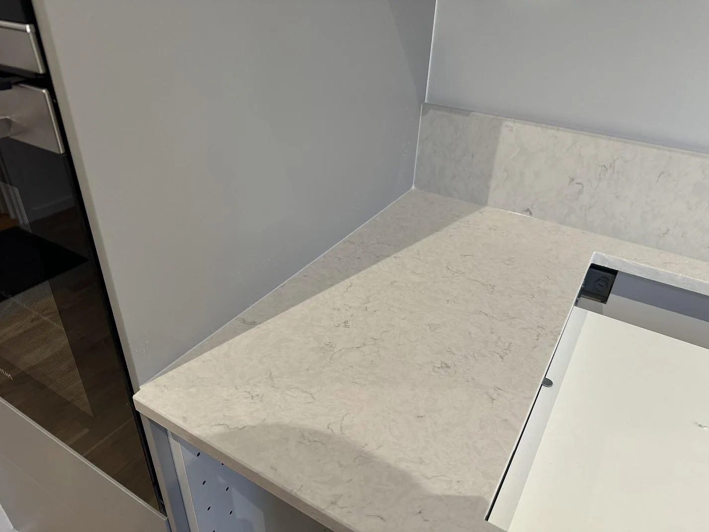 Sidoyta vid hällurtag i polerad Silestone Snowy Ibiza med ljus ådring och stenkant i kök i Staffanstorp.