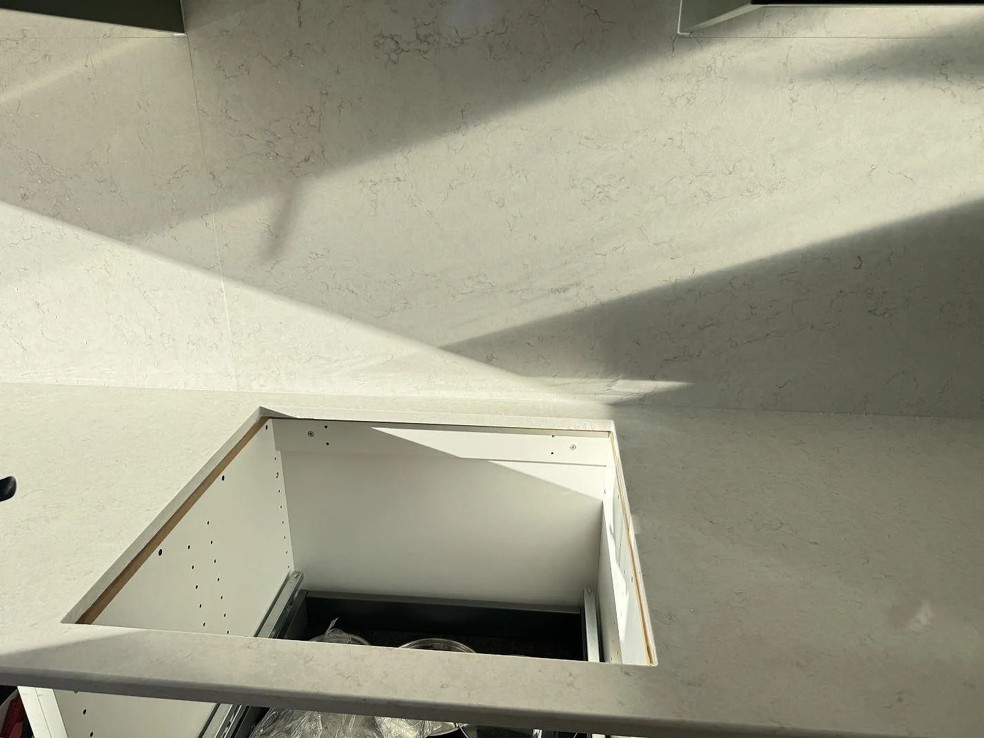 Topvy över polerad Silestone Snowy Ibiza bänkskiva med öppet hällurtag och stänkskydd i ett kök i Staffanstorp.