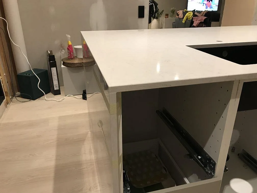 Köksbänkskiva i polerad Silestone Snowy Ibiza vid induktionshällen, monterad över öppna stommar i Steninge.