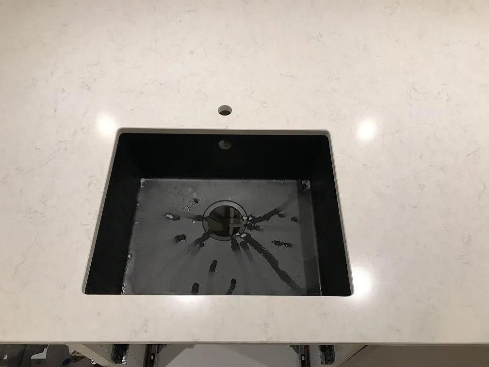Underlimmad svart kompositdiskho sedd ovanifrån i en bänkskiva av vit Silestone Snowy Ibiza i Steninge.