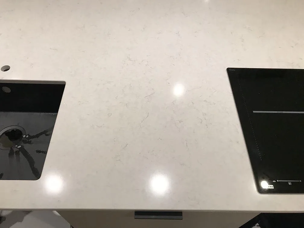 Köksbänkskiva i Silestone Snowy Ibiza, polerad, med urtag för diskho och induktionshäll och fin ljus ådring i Steninge.