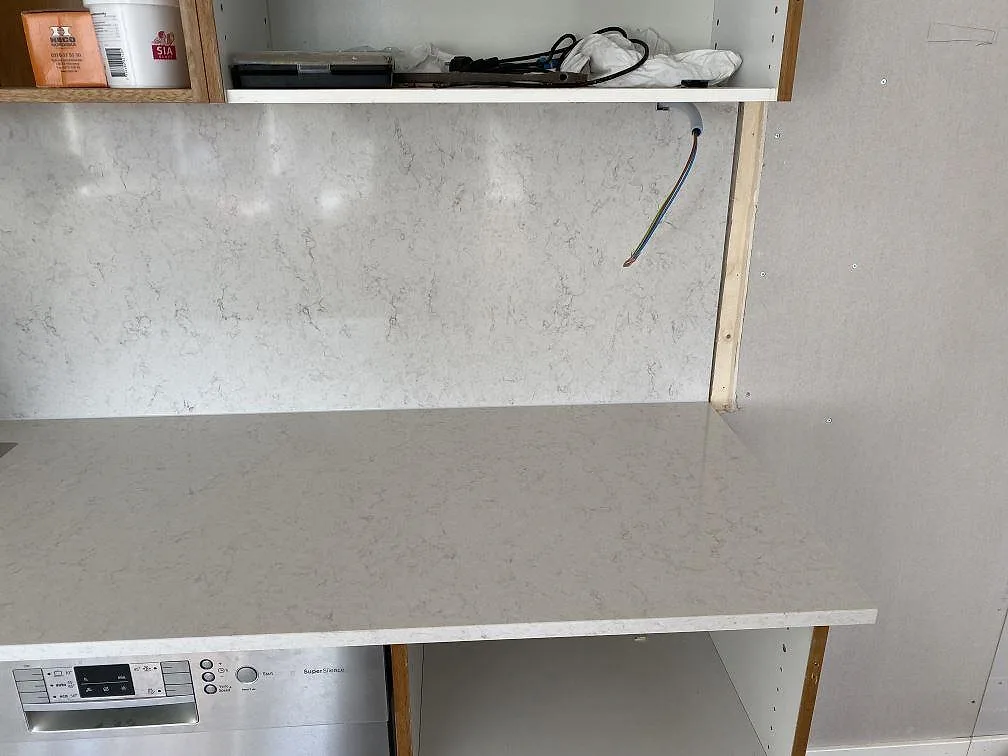 Köksbänkskiva i Silestone Snowy Ibiza med polerad väggbeklädnad mot vägg, fotograferad under montering i Steninge.