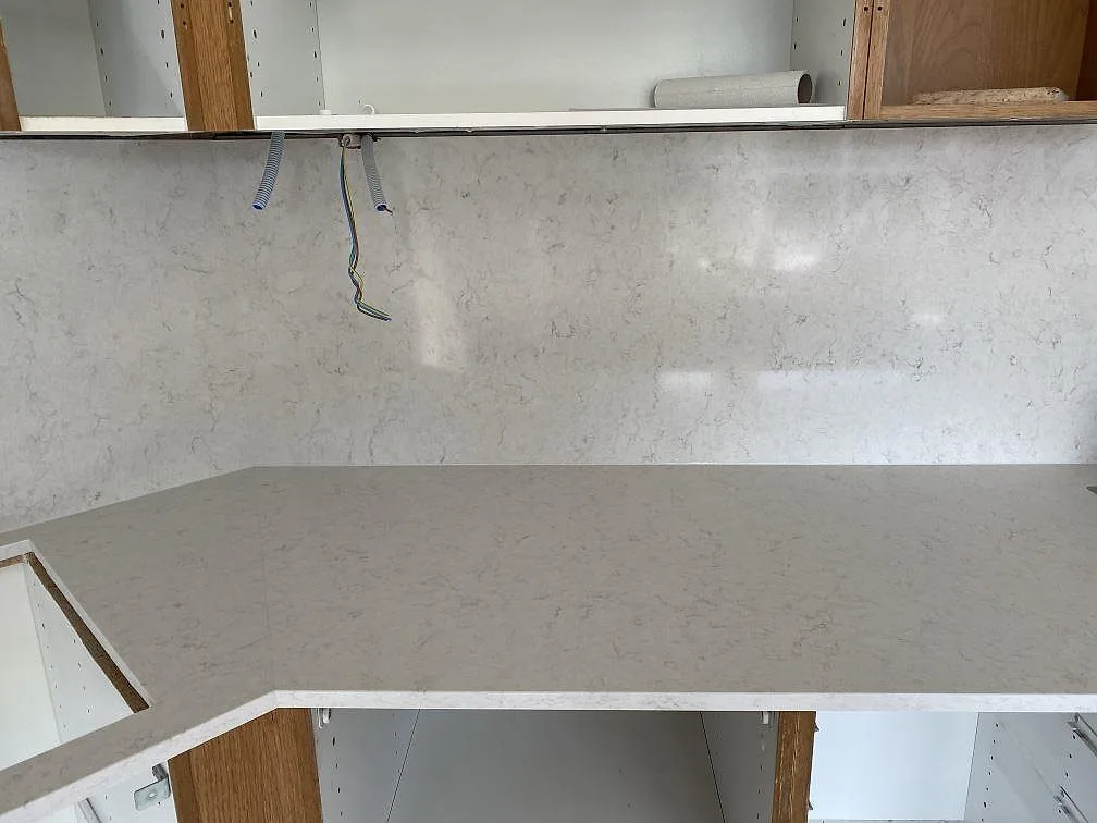 Polerad köksbänkskiva i Silestone Snowy Ibiza med uppdragen väggbeklädnad och mjuk grå ådring, fotograferad under montering i ett kök i Steninge.