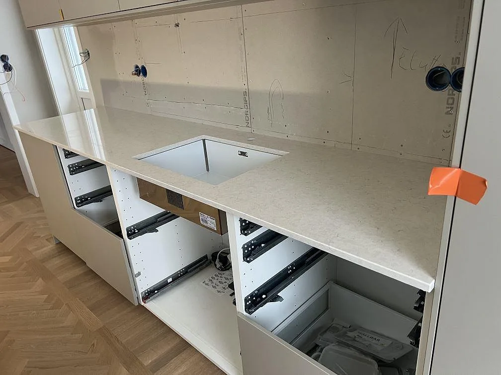 Närbild av polerad Silestone Snowy Ibiza bänkskiva med rektangulärt funktionsurtag och öppna köksstommar i Stigtomta.