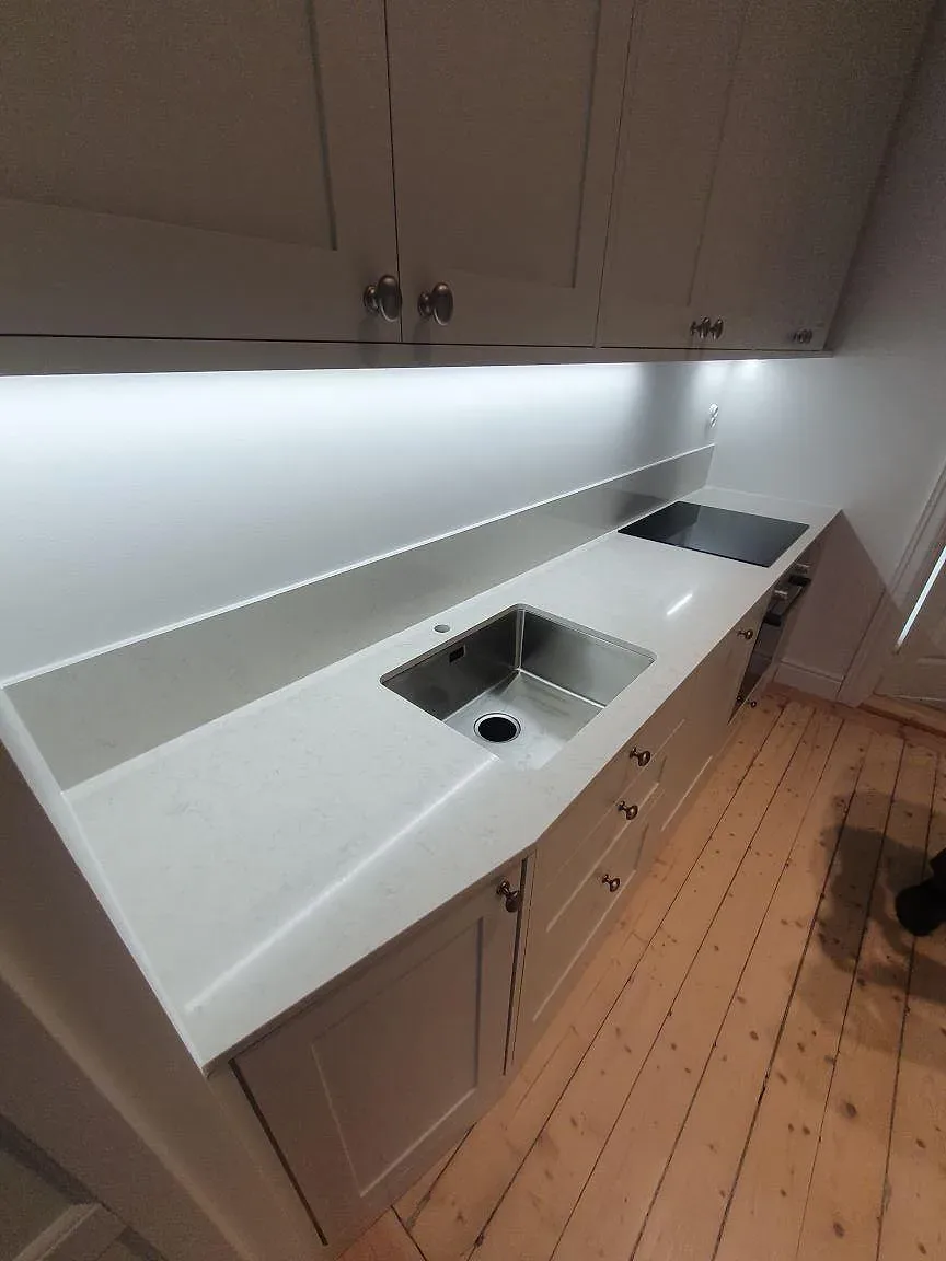 Ovanifrån visas köksbänkskivan i Silestone Snowy Ibiza med diskho, häll och uppvikt stänkkant i Stockholm.