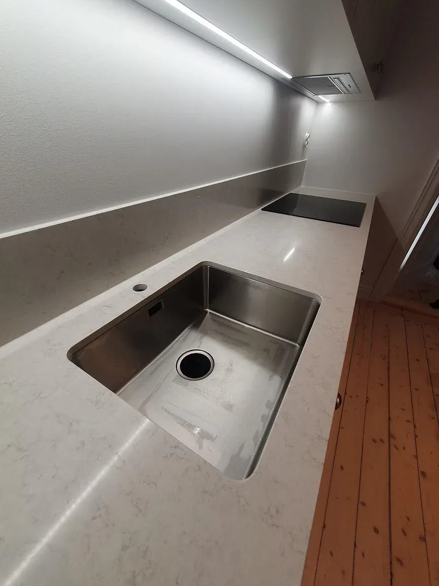 Närbild på polerad Silestone Snowy Ibiza med rostfri diskho och ljus ådring i köksbänkskivan i Stockholm.