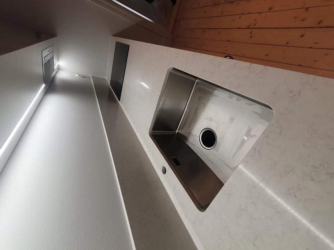 Närbild på underlimmad rostfri diskho i vit polerad Silestone Snowy Ibiza köksbänkskiva i Stockholm.