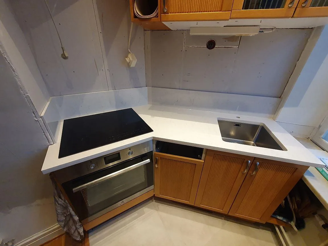 Köksbänkskiva i vit Silestone Snowy Ibiza, polerad komposit, med häll, rostfri diskho och låg stänkkant i ett kök i Stockholm.