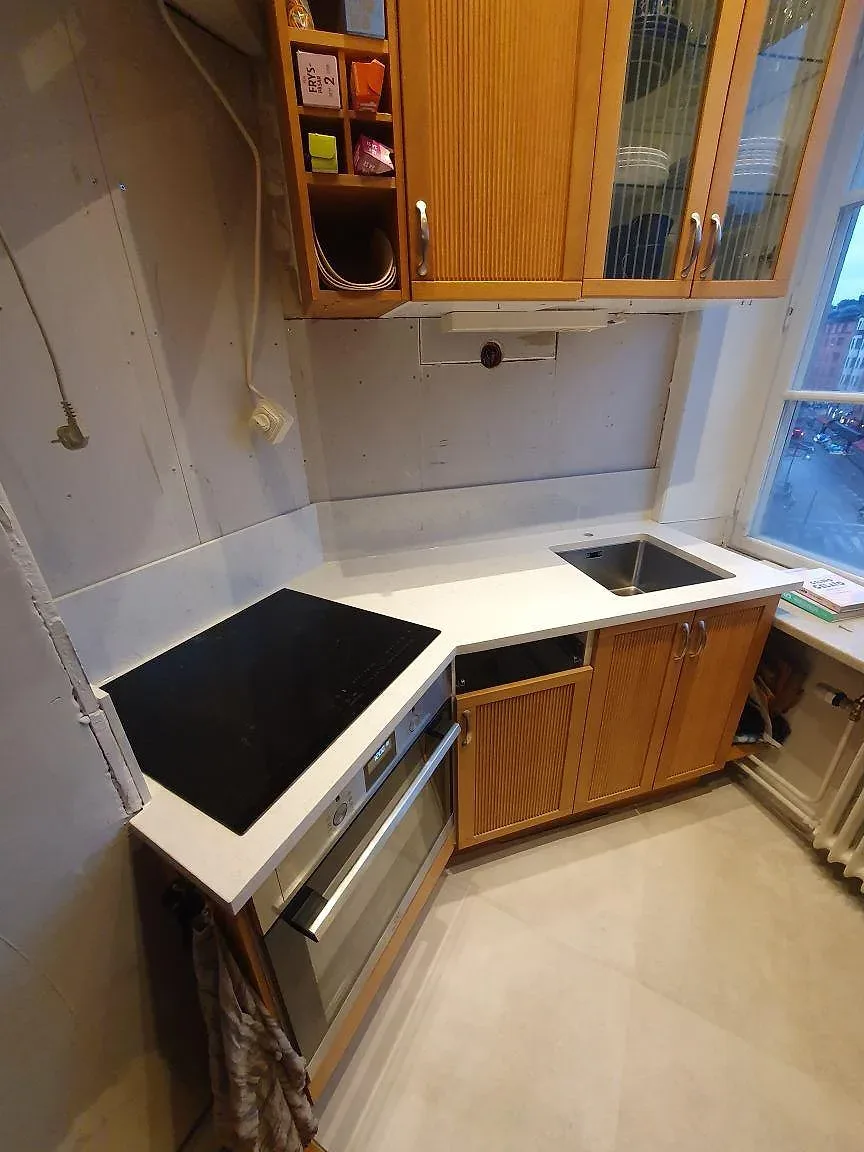 Köksbänkskiva i polerad vit Silestone Snowy Ibiza med stänkskydd i samma sten under montering i ett kök i Stockholm.