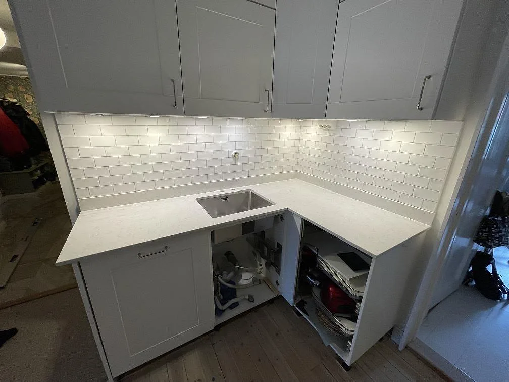 Diskho och arbetsyta i polerad Silestone Snowy Ibiza, vit kvartskomposit, i ett L-format kök i Stockholm.