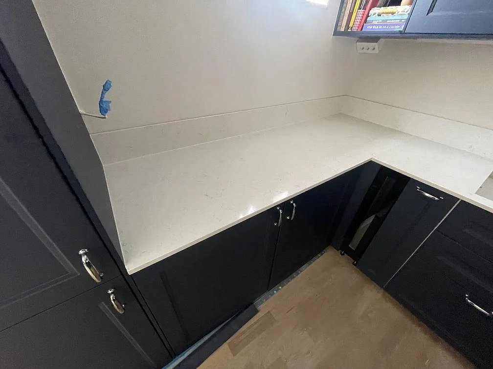 Hörnparti med polerad Silestone Snowy Ibiza, vit kompositbänkskiva och matchande stänkskydd i Stockholm.