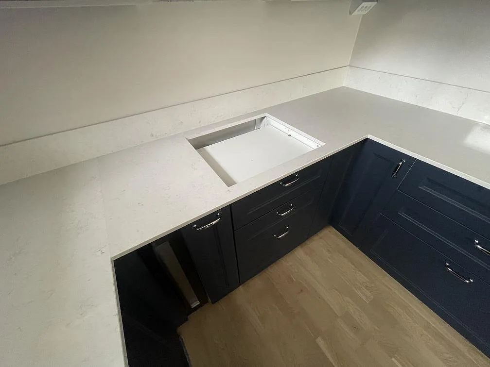 Hällöppning i polerad Silestone Snowy Ibiza med stänkskydd längs väggen i ett kök i Stockholm.