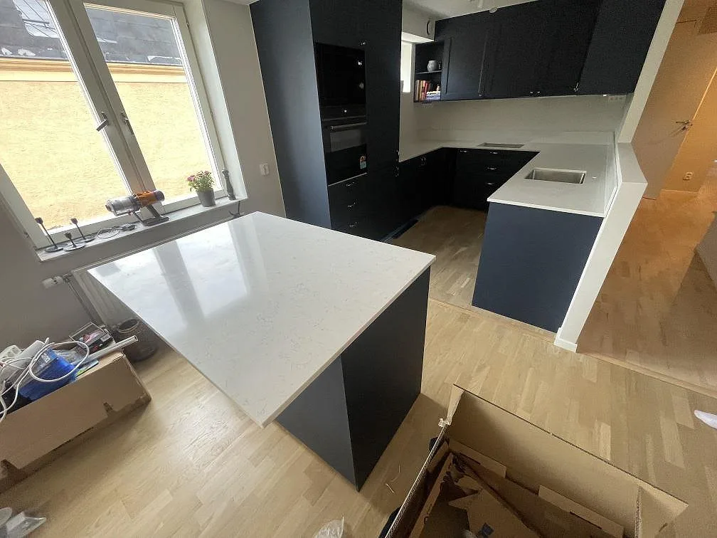 Översikt av kök i Stockholm med polerad Silestone Snowy Ibiza på L-formad bänk, diskho och separat köksö.