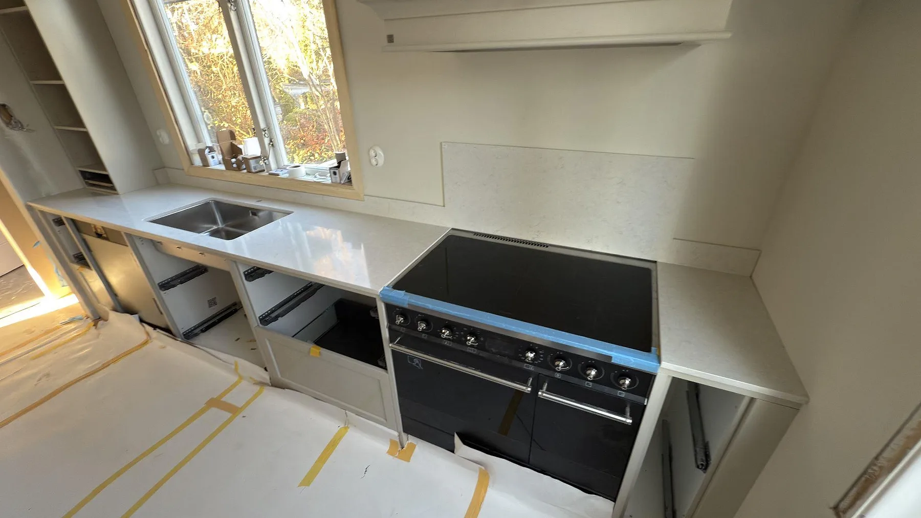 Polerad Silestone Snowy Ibiza som köksbänk med stänkskydd, rostfri diskho och spis i ett kök i Stockholm.