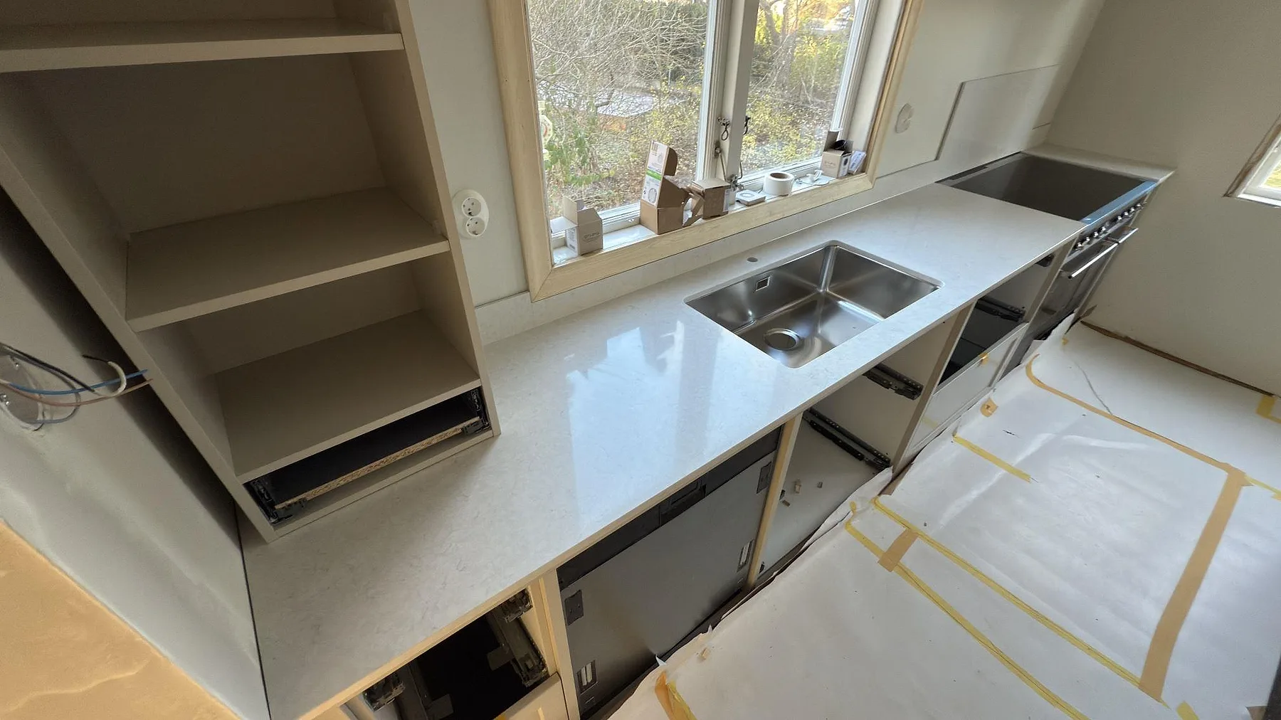 Köksbänk i polerad Silestone Snowy Ibiza med underlimmad rostfri diskho och stänkskydd vid fönster i Stockholm.