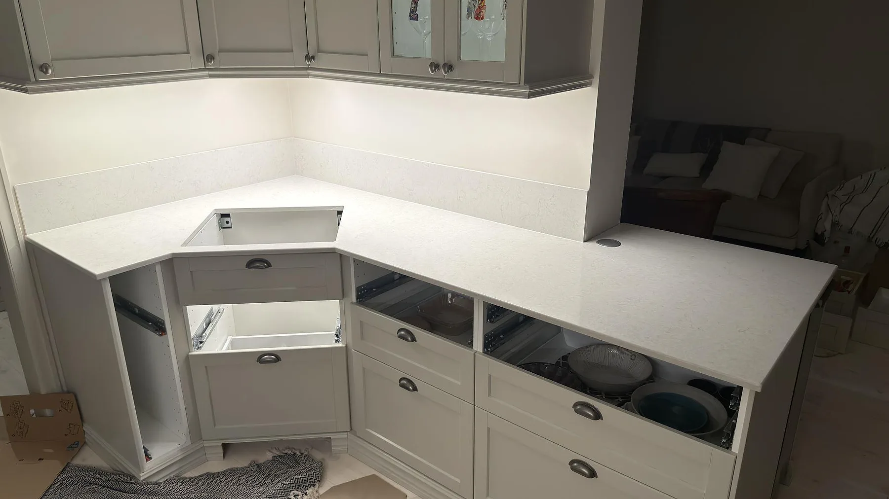L-formad köksbänkskiva i vit Silestone Snowy Ibiza, polerad, med hörnskåp, vitrinöverskåp och stänkkant i samma sten i ett kök i Stockholm.