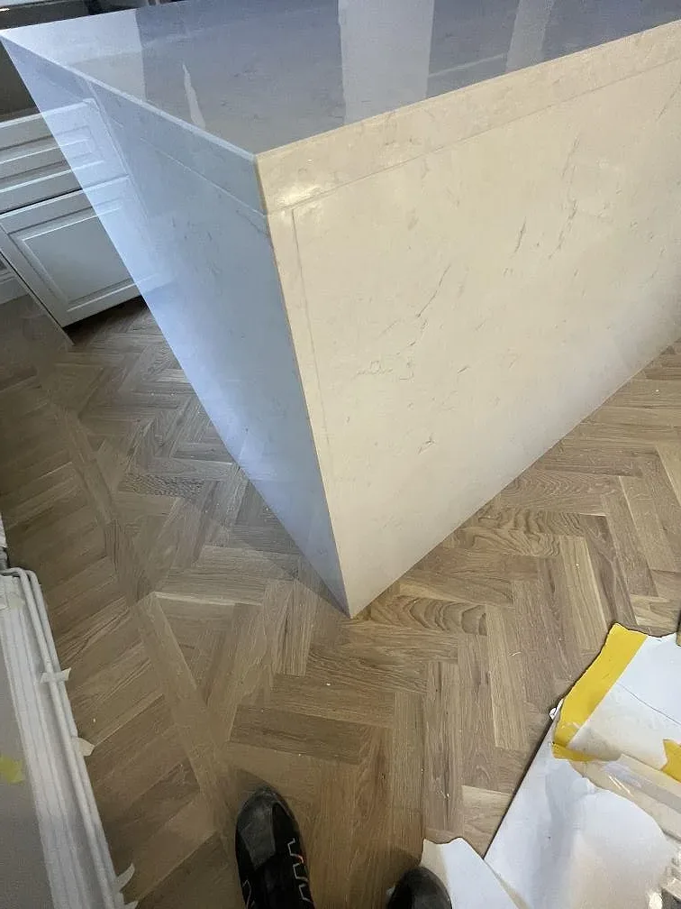 Halvö i vit Silestone Snowy Ibiza med gerad kant och lätt ådring, fotograferad under montering i ett kök i Stockholm.