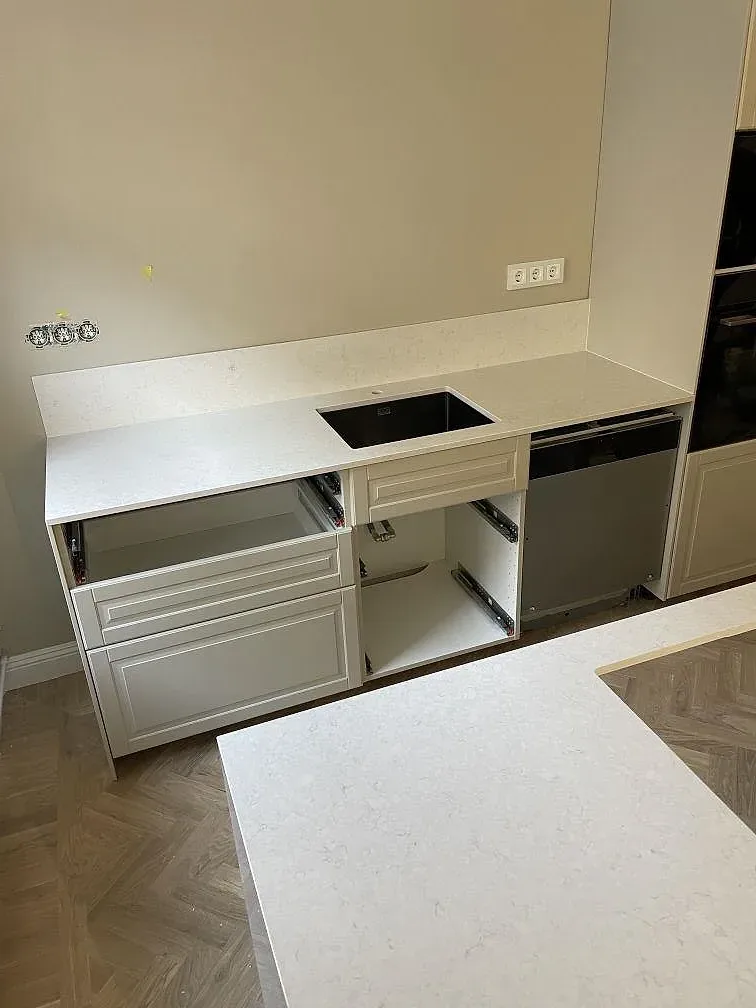 Köksdel med vit Silestone Snowy Ibiza bänkskiva och öppna köksstommar under montering i ett kök i Stockholm.