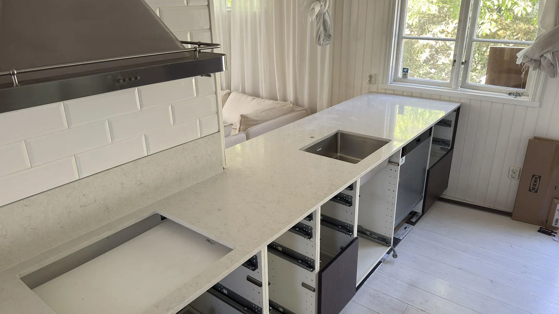 Köksbänkskiva i polerad Silestone Snowy Ibiza i Stockholm, undermonterad diskho och förberett hällurtag ovanför öppna stomlådor i köket.