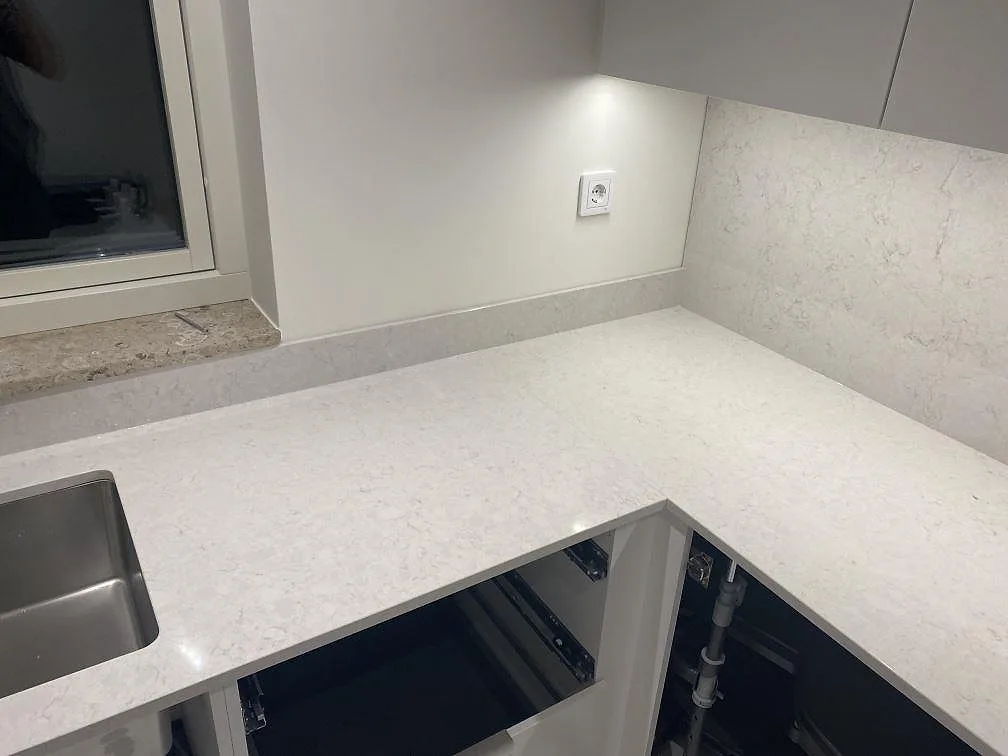 Hörnparti i köket i Strandbaden med polerad Silestone Snowy Ibiza som bänkskiva och stänkskydd, fotograferat under montering.