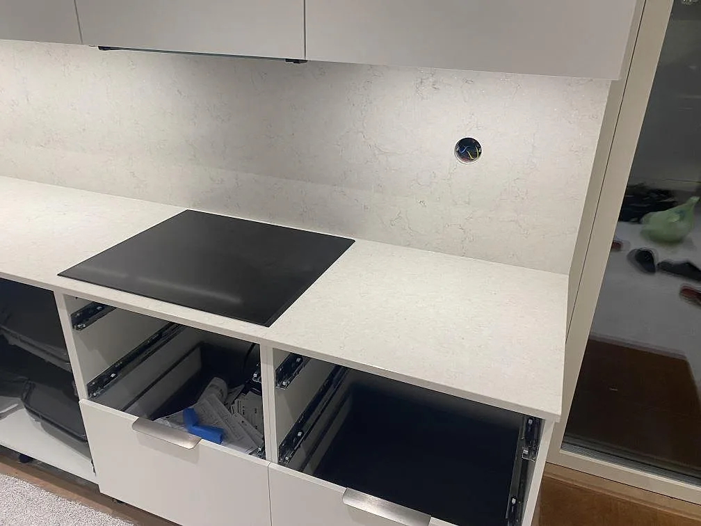 Detalj av hällsidan i Strandbaden med polerad Silestone Snowy Ibiza runt den svarta hällen och stänkskydd bakom.