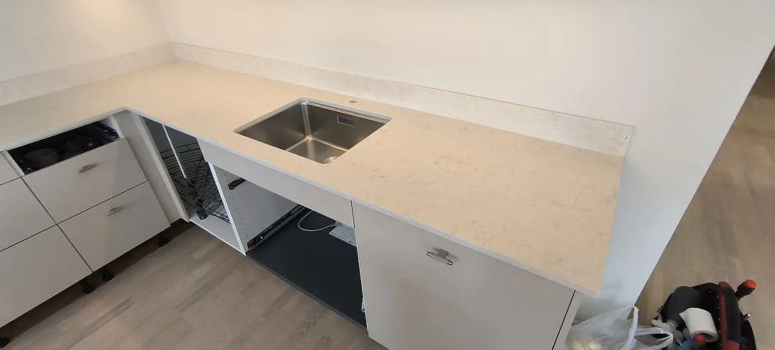 Matt köksbänkskiva i Silestone Snowy Ibiza komposit med låg stänkkant och öppna köksstommar i Sundbyberg.