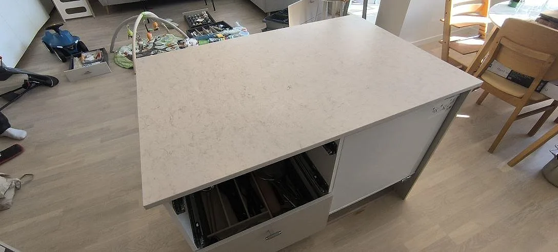 Närbild av köksö i matt Silestone Snowy Ibiza komposit med ljus ådring i ett kök i Sundbyberg.