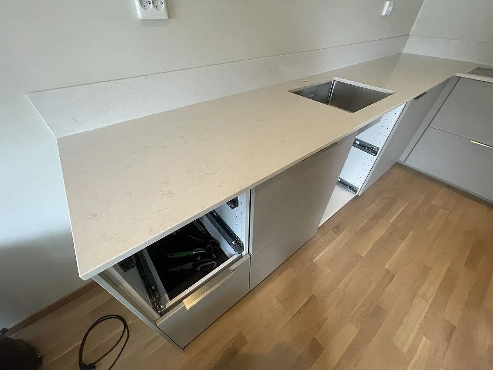 Närbild på vit polerad Silestone Snowy Ibiza som köksbänkskiva med diskho och låg stänkkant i ett kök i Sundbyberg.