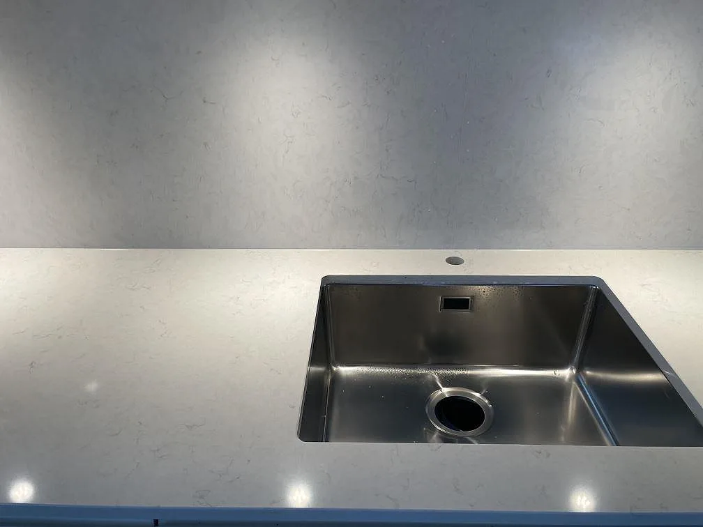 Underlimmad rostfri diskho infälld i vit Silestone Snowy Ibiza-bänkskiva, ovanifrån, i ett kök i Sundbyberg.