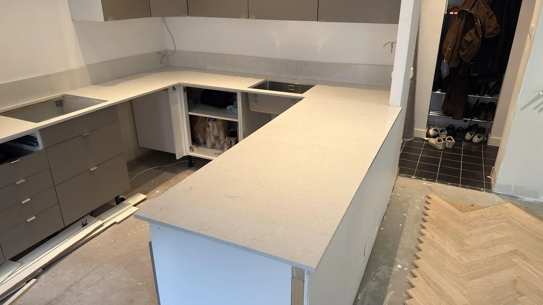 Vit polerad Silestone Snowy Ibiza bänkskiva med halvö och underlimmad rostfri diskho i ett kök i Sundbyberg, med uppvikt stänkskydd längs väggen.