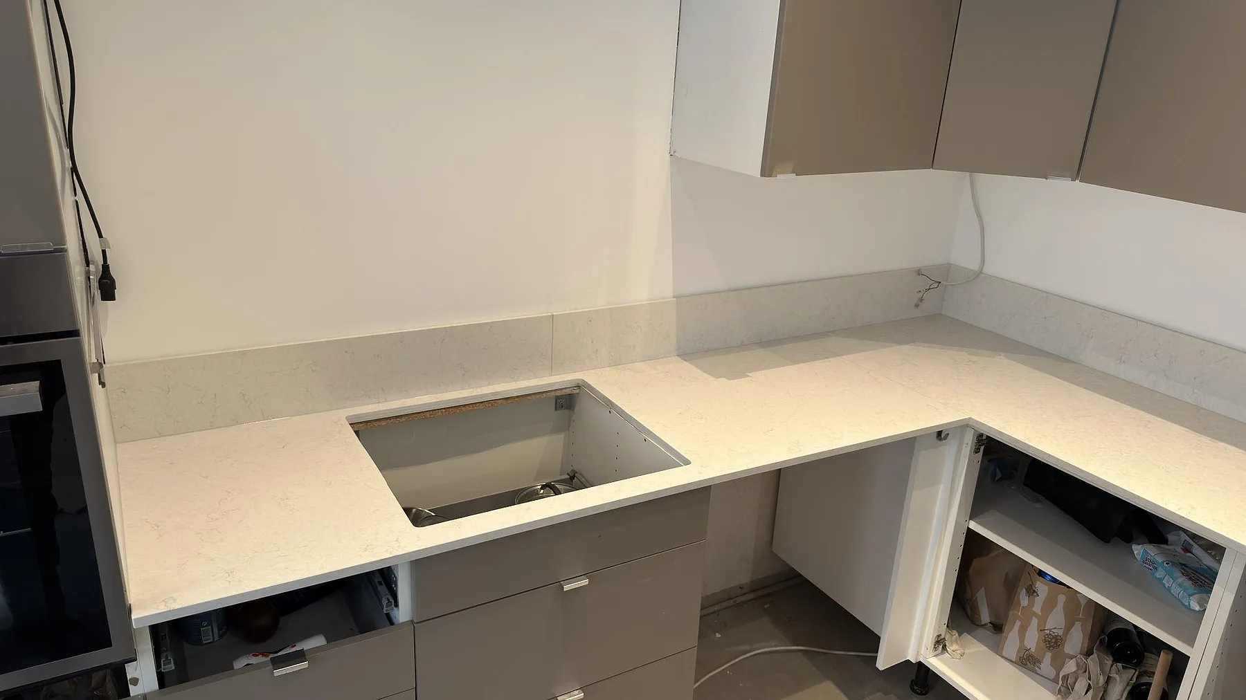 Närbild på polerad Silestone Snowy Ibiza bänkskiva i ett kök i Sundbyberg med urtag för häll och uppvikt 12 mm stänkskydd i samma vita kvartskomposit.