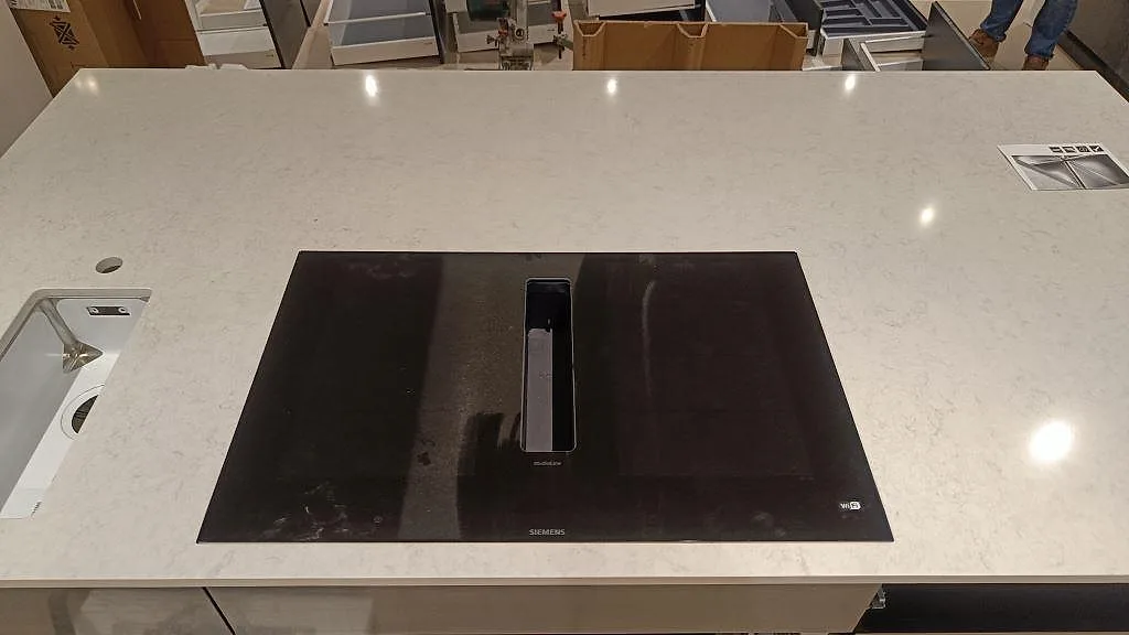 Köksö i Silestone Snowy Ibiza ovanifrån med svart Siemens induktionshäll och underlimmad diskho i ett kök i Svedala.