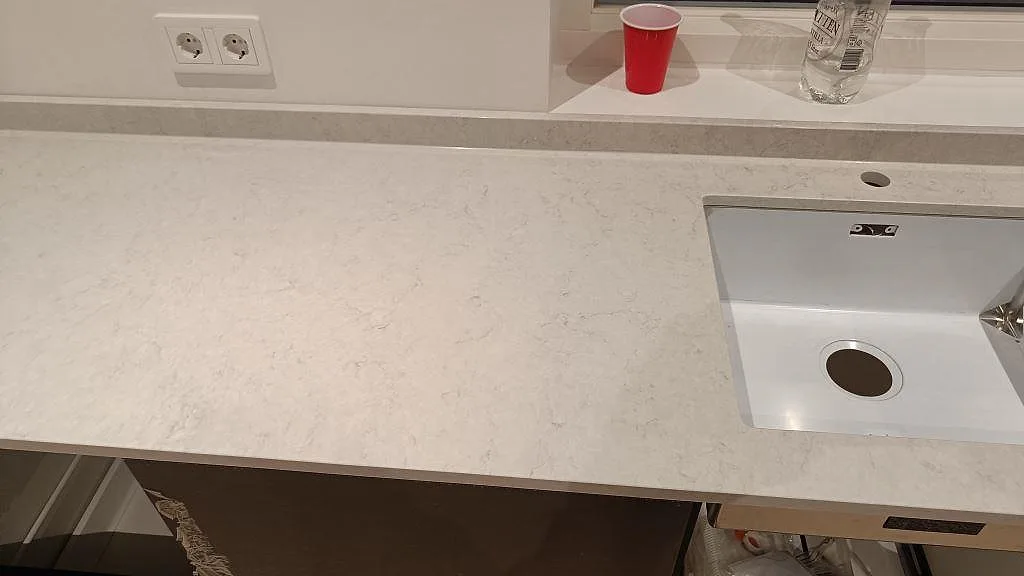 Bänkrad i Silestone Snowy Ibiza med underlimmad diskho, uppvikt stänkkant och fönster i ett kök i Svedala.