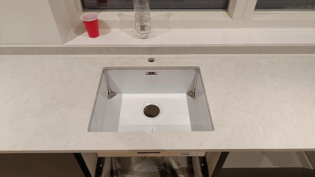Underlimmad diskho ovanifrån i polerad Silestone Snowy Ibiza bänkskiva med uppvikt stänkkant i ett kök i Svedala.
