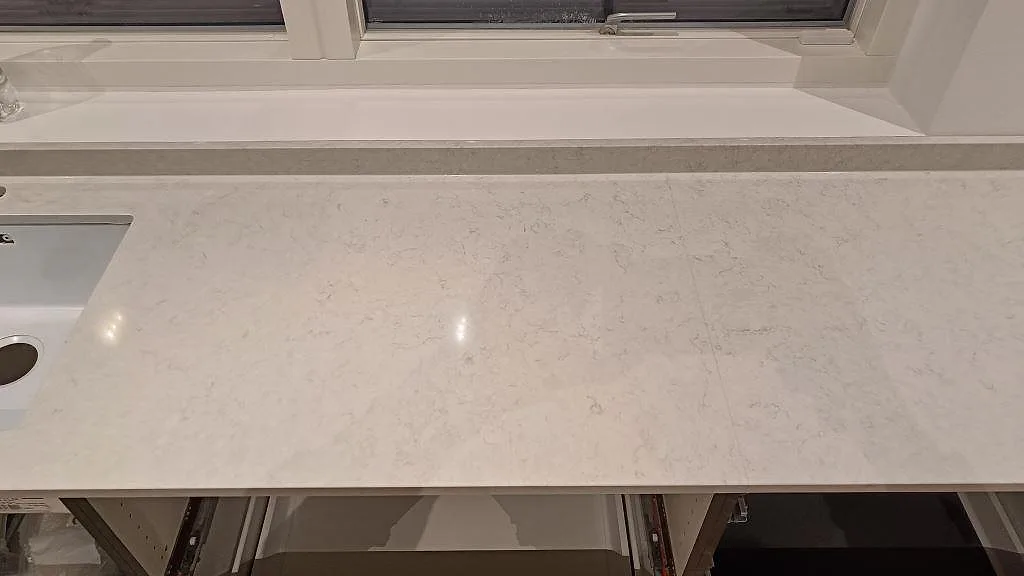 Detalj av grå marmorering i polerad Silestone Snowy Ibiza bänkskiva med uppvikt stänkkant i ett kök i Svedala.