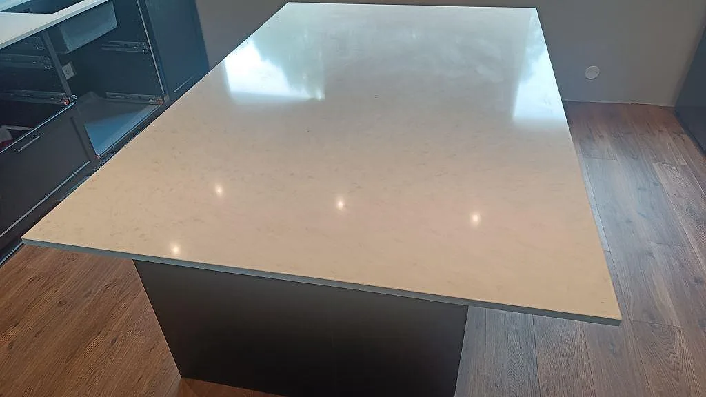 Stor köksö i polerad Silestone Snowy Ibiza med blank ljus kvartskomposityta och mörk bas i Svedala.
