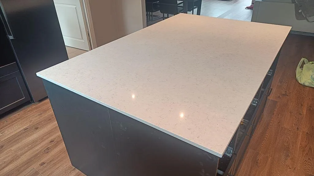 Rektangulär köksö i polerad Silestone Snowy Ibiza, ljus kvartskomposit mot mörk köksinredning i Svedala.