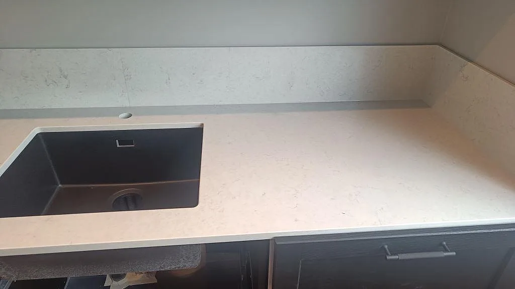 Arbetsyta i polerad Silestone Snowy Ibiza med mörk diskho under stenen och uppvikt stänkkant i Svedala.