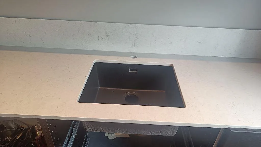 Underlimmad mörk diskho i polerad Silestone Snowy Ibiza med låg stänkkant i ett kök i Svedala.
