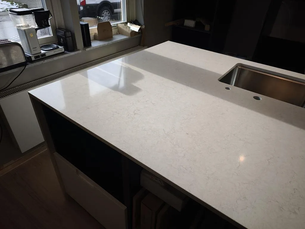 Närbild av polerad Silestone Snowy Ibiza komposit med mjuk ådring och rostfri diskho i ett kök i Svedala.