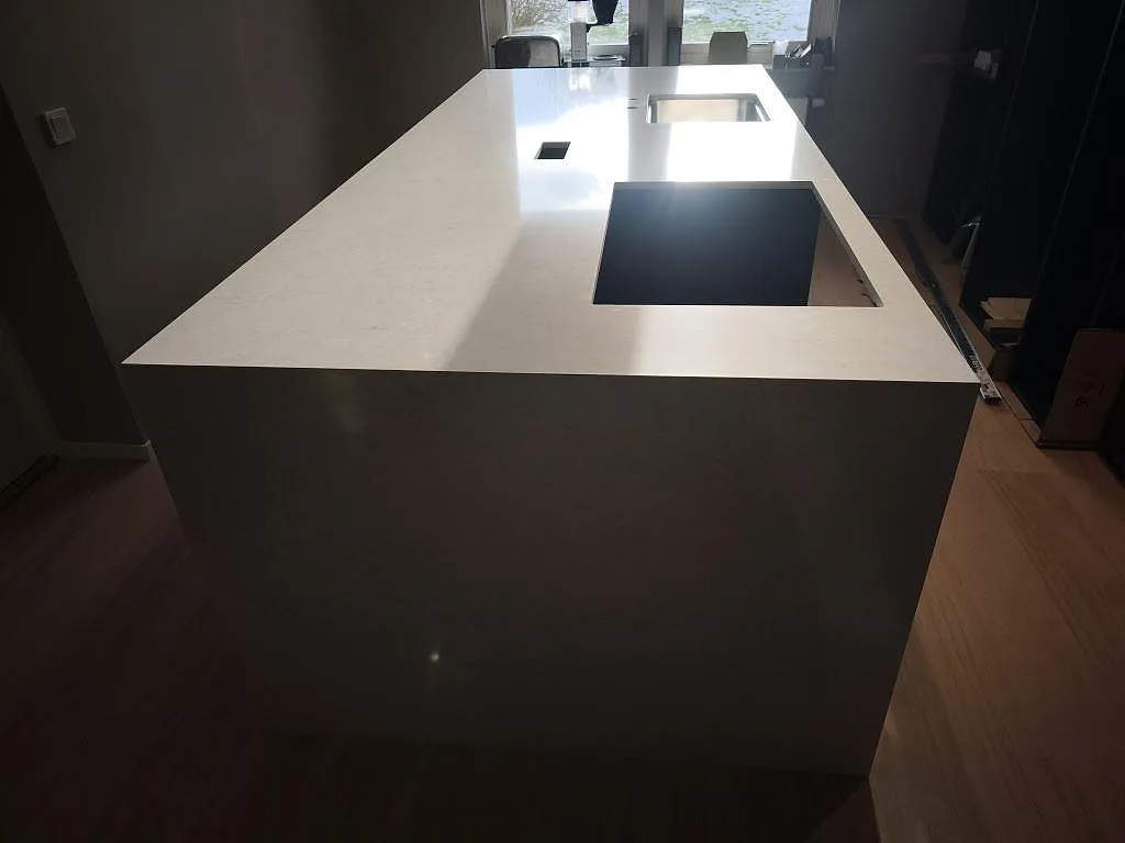Rak köksbänkskiva i Silestone Snowy Ibiza, polerad komposit, med hällurtag och diskho under montering i Svedala.