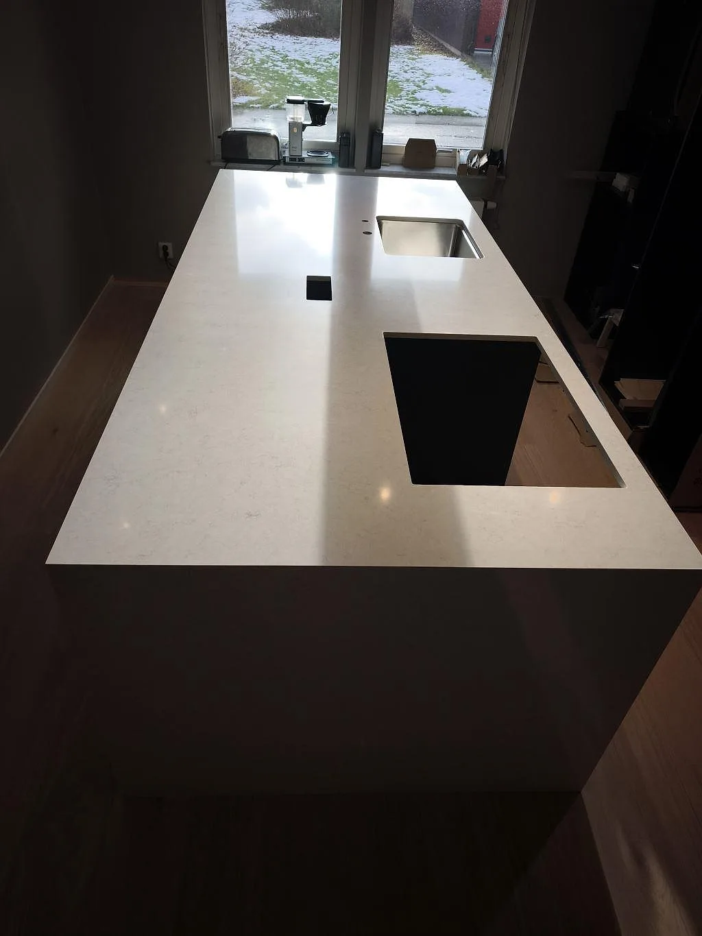 Vit köksbänkskiva i Silestone Snowy Ibiza, polerad, sedd från gaveln med diskho och hällurtag i Svedala.
