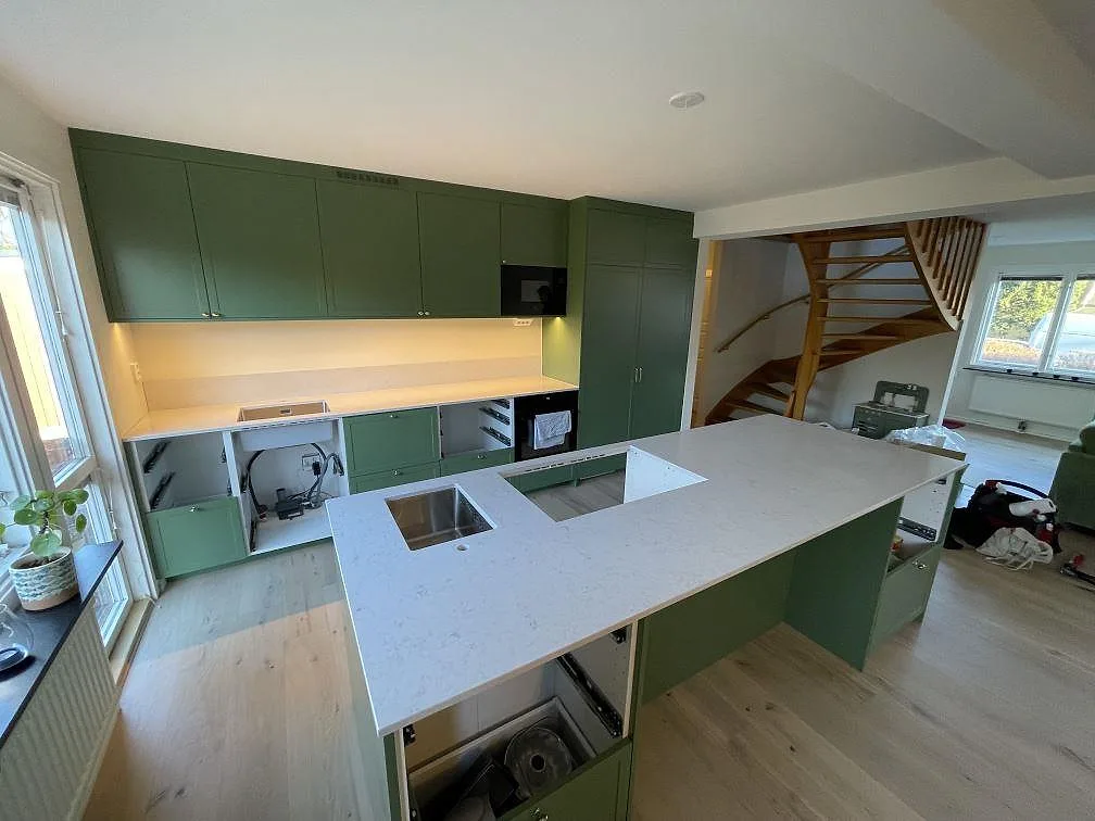 Översikt av ett kök i Täby med vit Silestone Snowy Ibiza som bänkskiva, diskhoöppning, hällurtag och låg stänkkant mot bakväggen.