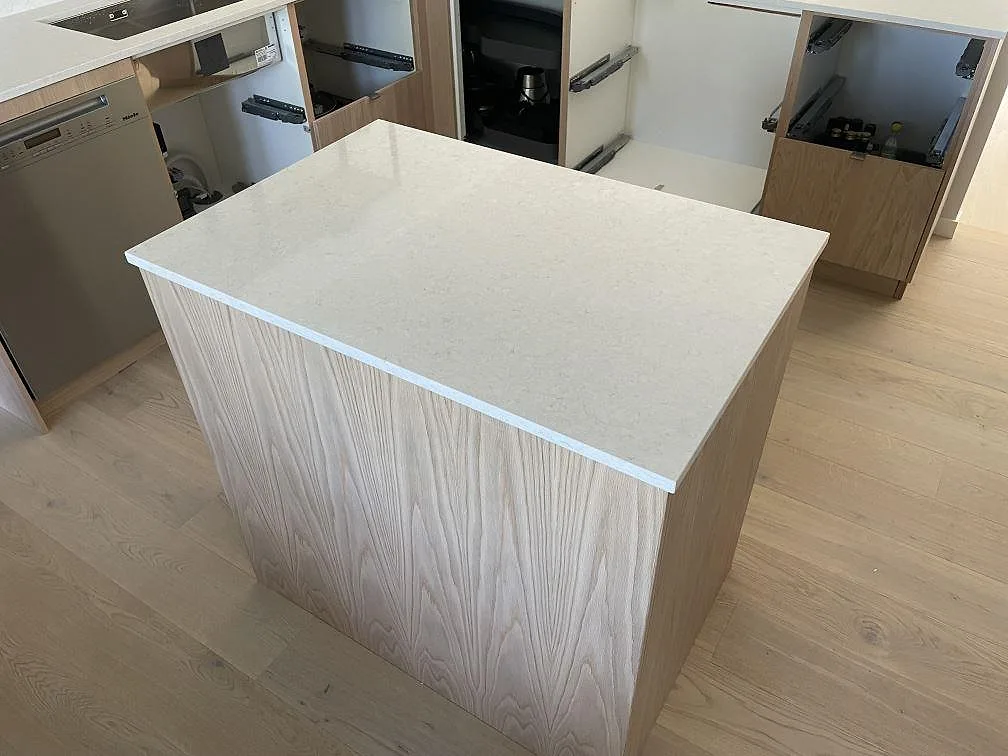 Köksö med bänkskiva i polerad Silestone Snowy Ibiza-komposit, ljus sten med mild ådring i Täby.