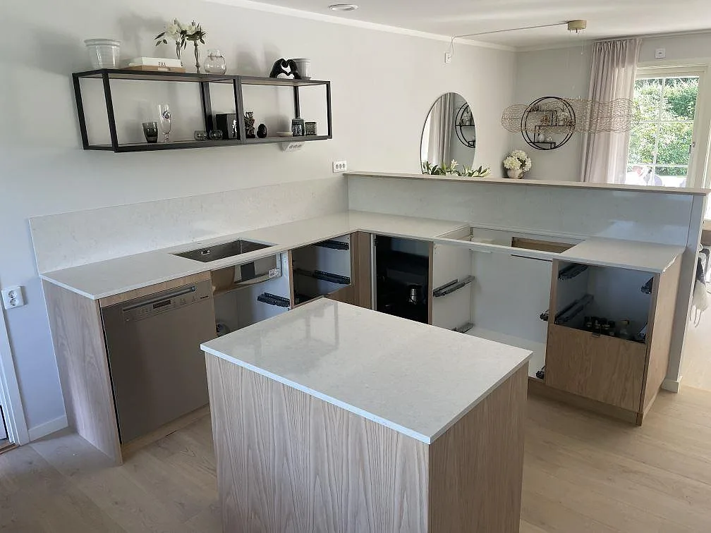 Polerad köksbänkskiva i Silestone Snowy Ibiza-komposit med köksö, diskho, häll och stänkskydd i ett kök i Täby.