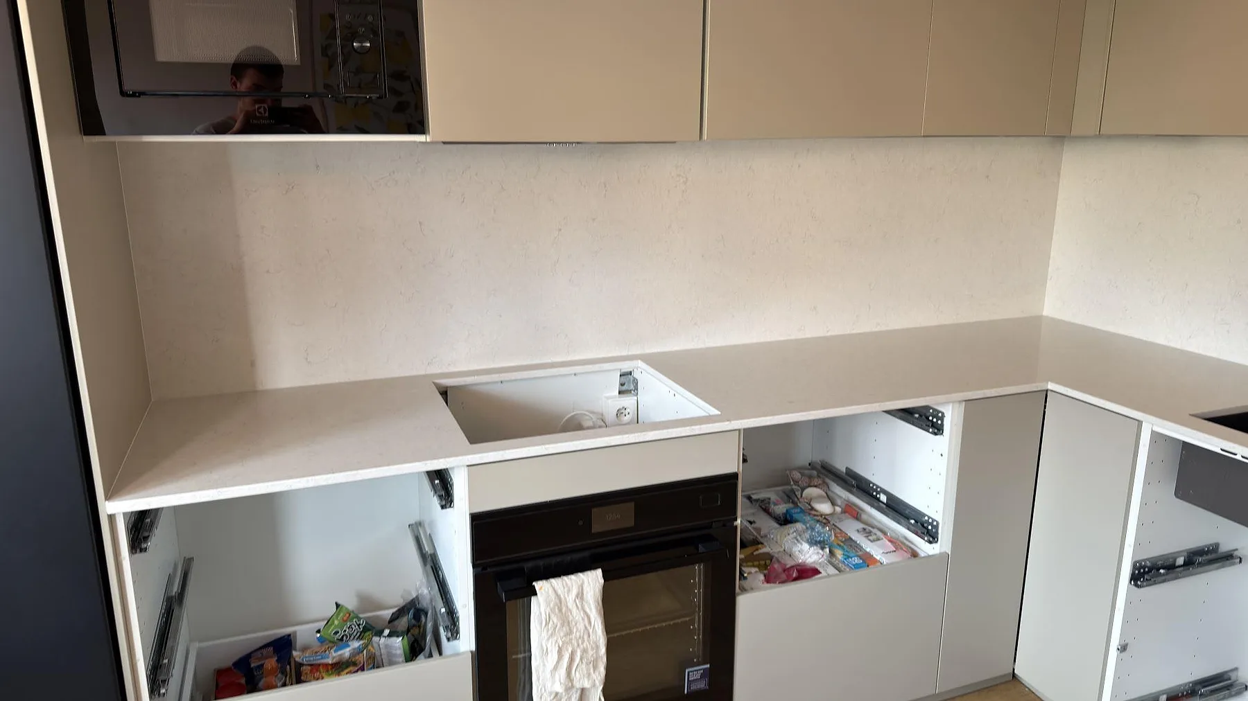 Polerad köksbänkskiva i Silestone Snowy Ibiza med urtag i bänken och samma sten på väggen i Täby.