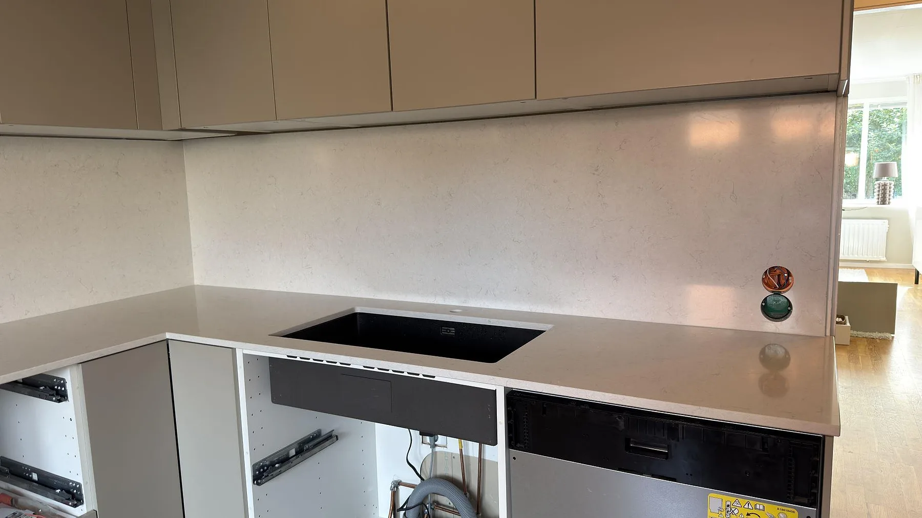 Närbild på polerad Silestone Snowy Ibiza som köksbänk och stänkskydd vid den svarta hozonen i ett kök i Täby.