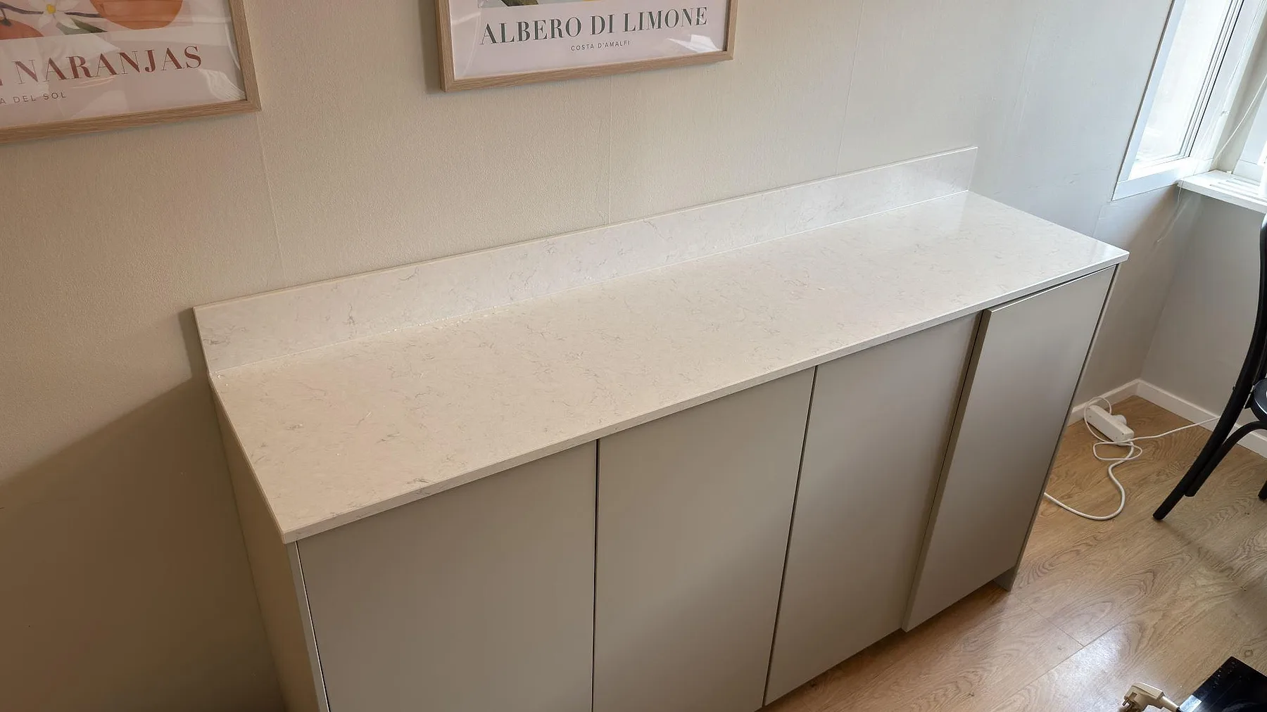 Lång avställningsbänk i polerad Silestone Snowy Ibiza med låg stänkkant och ljus ådring i Täby.