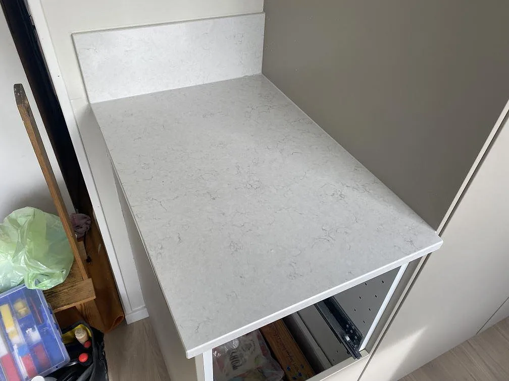 Kort köksbänkskiva i polerad Silestone Snowy Ibiza kvartskomposit med lågt stänkskydd och ljus ådring i Tingsryd.